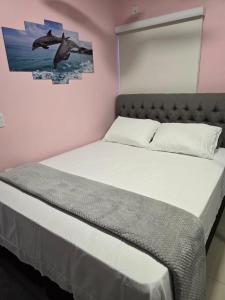 Casa Rosa في كويابا: سرير في غرفة نوم مع صورة الدلافين على الحائط