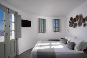 a white bedroom with a bed and a tv at The Sunset Windmill in Oia