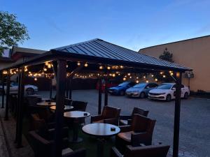 a group of tables and chairs under a pavilion with parked cars at Ambassador Hotel in Timişoara