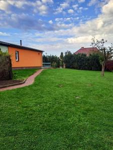 a yard with a house and a grass field at Ferienunterkunft Henneberg mit Garten am Kummerower See in Neukalen