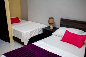 2 łóżka z czerwonymi poduszkami w pokoju w obiekcie RUTA DEL MAR INN HOTEL w mieście Santa Marta