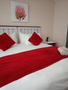 Edladleni Guesthouse Quigney في شرق لندن: غرفة نوم مع بطانية حمراء على سرير أبيض