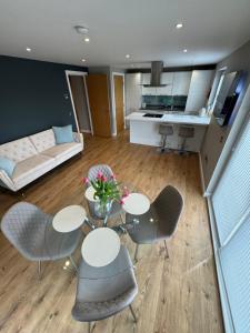 a living room with a table and chairs and a kitchen at IVI Granton Harbour Apartment in Edinburgh