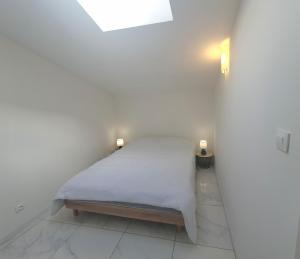 Grand-Village-PlageにあるBeau studio à Oléronの白い部屋のベッド1台(2つの照明付)