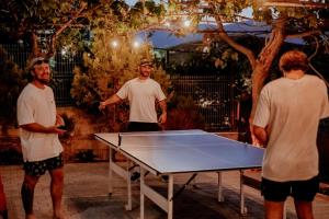 un grupo de hombres parados alrededor de una mesa de ping pong en Berat Backpackers Hostel, en Berat