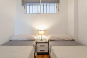 1 dormitorio con 2 camas y mesita de noche con lámpara en Precioso apartamento, en Santa Pola