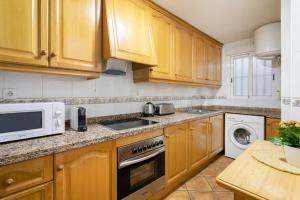 a kitchen with wooden cabinets and a sink and a microwave at Precioso apartamento in Santa Pola