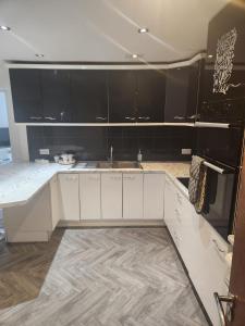 uma cozinha com armários brancos e um lavatório em Sariyu space em Dagenham