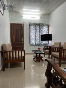 a living room with chairs and a flat screen tv at NATURE FAMILY HOMESTAY in Munnar