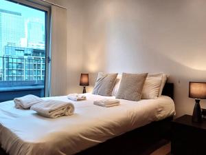 a bedroom with a large bed with towels on it at Canary Wharf Serviced Apartments in London