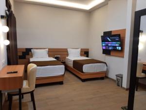 Cette chambre comprend deux lits, un bureau et une télévision. dans l'établissement Griya Endika Syariah, à Yogyakarta