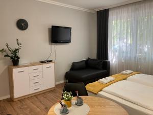 um quarto de hotel com uma cama, um sofá e uma televisão em ILLA Apartments em Eger