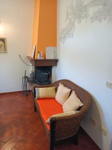 een rieten stoel met een oranje kussen in een kamer bij Il Mandorlino Pitigliano appartamento in tipico casale maremmano con portico e giardino in Pitigliano