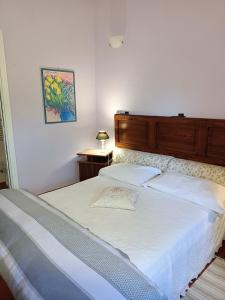 a bedroom with a white bed with a wooden headboard at Il Mandorlino Pitigliano appartamento in tipico casale maremmano con portico e giardino in Pitigliano