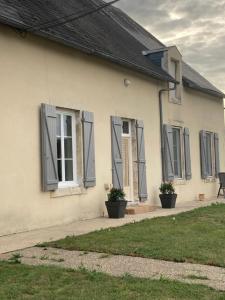 サン・モールにあるLa petite fermetteの灰色のシャッター付き窓と植物のある白い家