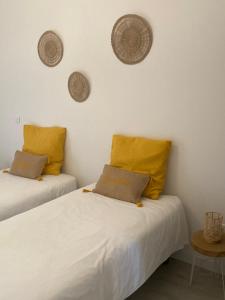 2 bedden met gele kussens in een kamer bij La petite fermette in Saint-Maur