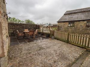 a patio with a table and chairs next to a building at Boskins in Sedbergh