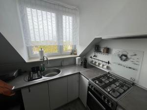 a kitchen with a sink and a stove and a window at Attic close to the beach and city center in Kołobrzeg