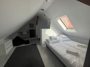 a white bedroom with a bed and a window at Attic close to the beach and city center in Kołobrzeg