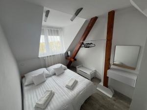 a bedroom with a bed with white sheets and pillows at Attic close to the beach and city center in Kołobrzeg