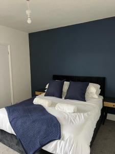 a bedroom with a large bed with a blue wall at House Next to the Station in Watford