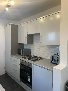 a kitchen with white cabinets and a stove top oven at House Next to the Station in Watford