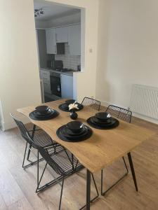 a wooden table with black chairs and a kitchen at House Next to the Station in Watford