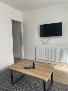 a living room with a wooden table and a flat screen tv at House Next to the Station in Watford