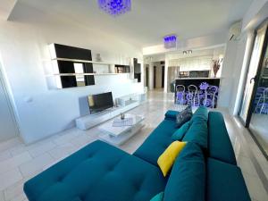 Una sala de estar con un sofá azul y una cocina. en SOPHIA LAKE VIEW SUITE, en Mamaia
