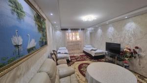 una sala de estar con muebles blancos y una pintura en la pared en Boulevard Apartment, en Samarkand