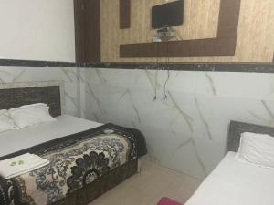 um quarto com duas camas e uma televisão na parede em Gopesh Dham em Vrindavan