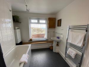 a bathroom with a tub and a sink at THE PENTHOUSE APARTMENT with an 18ft by 14ft balcony with amazing VIEWS over ST IVES HARBOUR and BAY perfect from Alfresco dining and sunbathing, ONSITE PARKING, LARGER GROUPS book our connecting apartments in St Ives