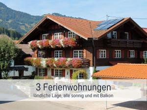 una casa con flores y paneles solares. en Biohof Burger, 3 sonnige Fewo, alle mit Balkon, Spielzimmer, Grillhütte, 7 km vor Oberstdorf en Bolsterlang