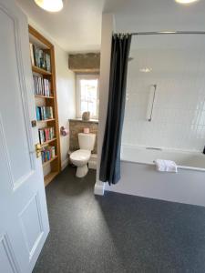 a bathroom with a toilet and a bath tub at THE PENTHOUSE APARTMENT with an 18ft by 14ft balcony with amazing VIEWS over ST IVES HARBOUR and BAY perfect from Alfresco dining and sunbathing, ONSITE PARKING, LARGER GROUPS book our connecting apartments in St Ives