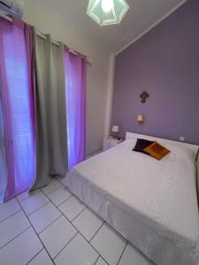 a bedroom with a white bed and purple curtains at Lefki's House in Agiokampos
