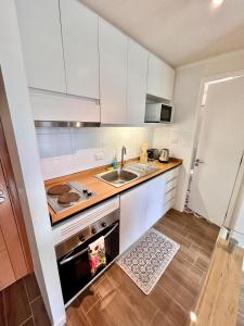 uma pequena cozinha com armários brancos e um lavatório em 201/ Precioso apartamento 1D+1B Centro + Jumbo 5 min em Puerto Montt