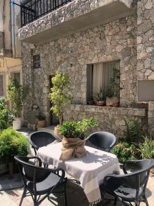 un patio con mesa, sillas y pared de piedra. en Guest House Pauline en Cos