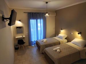 a hotel room with two beds and a television at Cavo Garden in Kavos