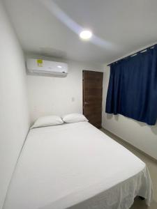 a bedroom with a white bed and a blue curtain at HOTEL DI MAR in Cartagena de Indias