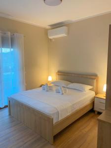 a bedroom with a bed with white sheets and a window at Villa Tabaku in Berat