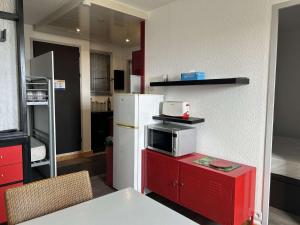 uma cozinha com um frigorífico e um micro-ondas num armário vermelho em Appartement Fleury-Saint-Pierre-la-Mer, 2 pièces, 6 personnes - FR-1-229D-626 em Saint Pierre La Mer