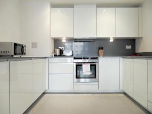 een witte keuken met witte kasten en apparaten bij Tower Hill Serviced Apartments in Londen