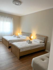 two beds in a hotel room with two lamps at Villa Tabaku in Berat