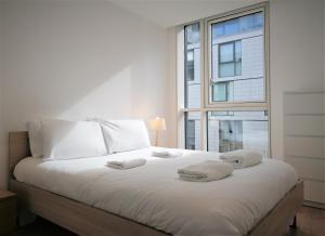 a bedroom with a white bed with a large window at Tower Hill Serviced Apartments in London