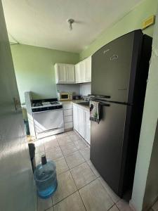 a kitchen with a black refrigerator and white cabinets at casa nagüera in Nagua