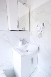 Baño blanco con lavabo y espejo en Hotel Boutique BUZI, en Berat