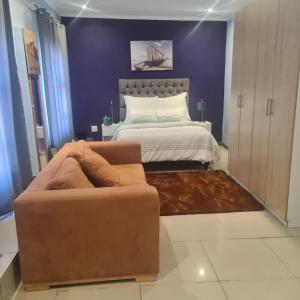 a bedroom with a bed and a couch and a bed at AR : Homestay Accommodation Goodwood in Cape Town