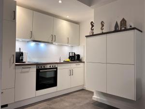 a kitchen with white cabinets and a stove top oven at Apartmenthaus am Nordseestrand, Whg 3, An der Rennweide 1B, 75qm in Dangast