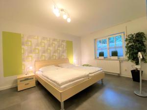 a bedroom with a bed and a plant and a window at Apartmenthaus am Nordseestrand, Whg 3, An der Rennweide 1B, 75qm in Dangast