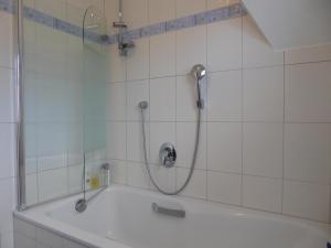 La salle de bains carrelée de blanc est pourvue d'une douche et d'une baignoire. dans l'établissement Haus Pier 24 An der Rennweide 24a 96qm, à Dangast 14 autres photos